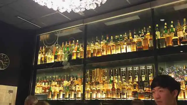More shelves lamp-packed with bottles of Scotch